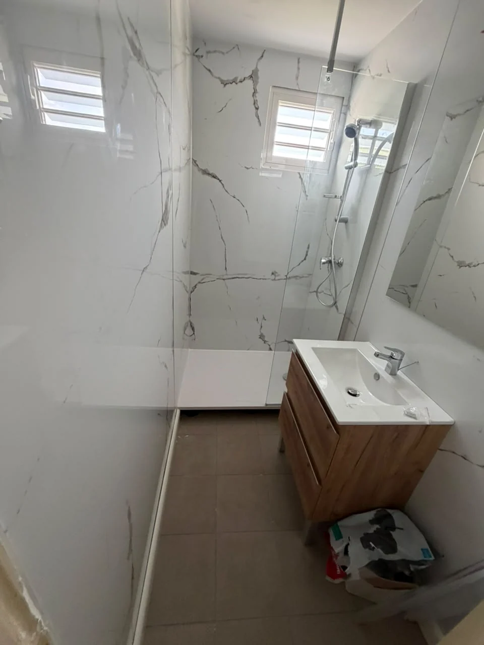 Salle de bain rénovée à Paradis avec panneaux muraux effet marbre et douche vitrée